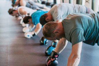 People in a boxing gym doing push-ups while wearing boxing gloves