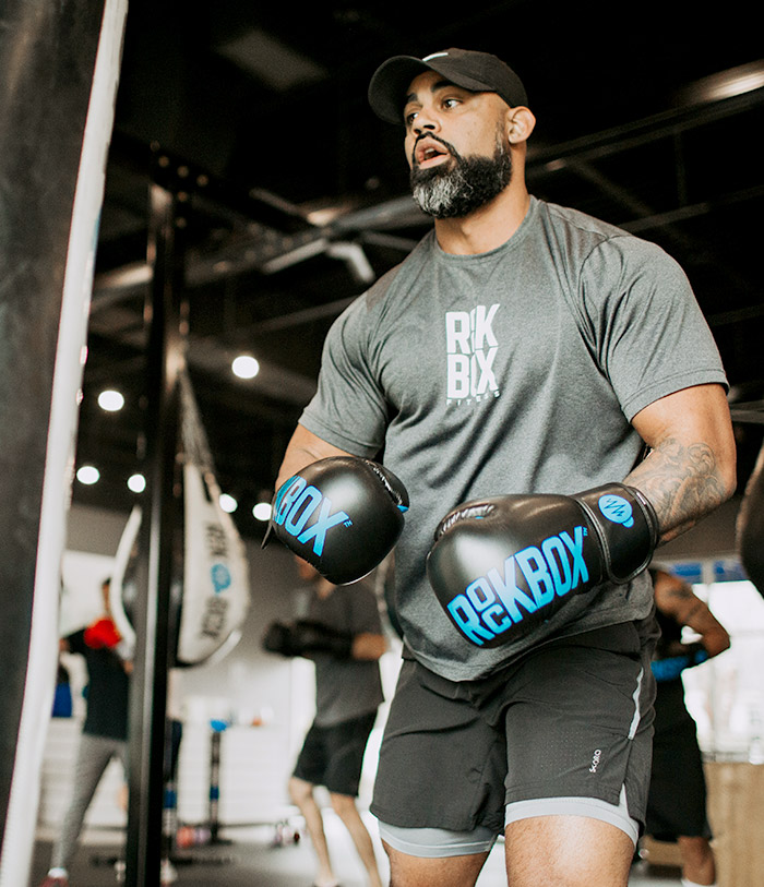 Man wearing boxing gloves looking winded during a workout