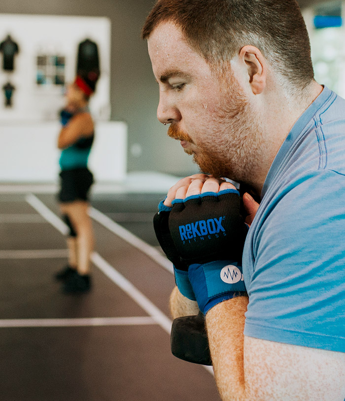 man wearing RockBox gloves holding weight and sweating while working out