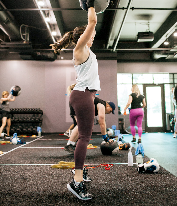 woman reaching up while holding weighted ball