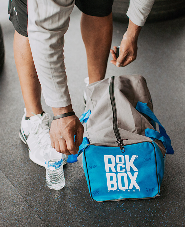 Man reaching down to RockBox Fitness duffel bag